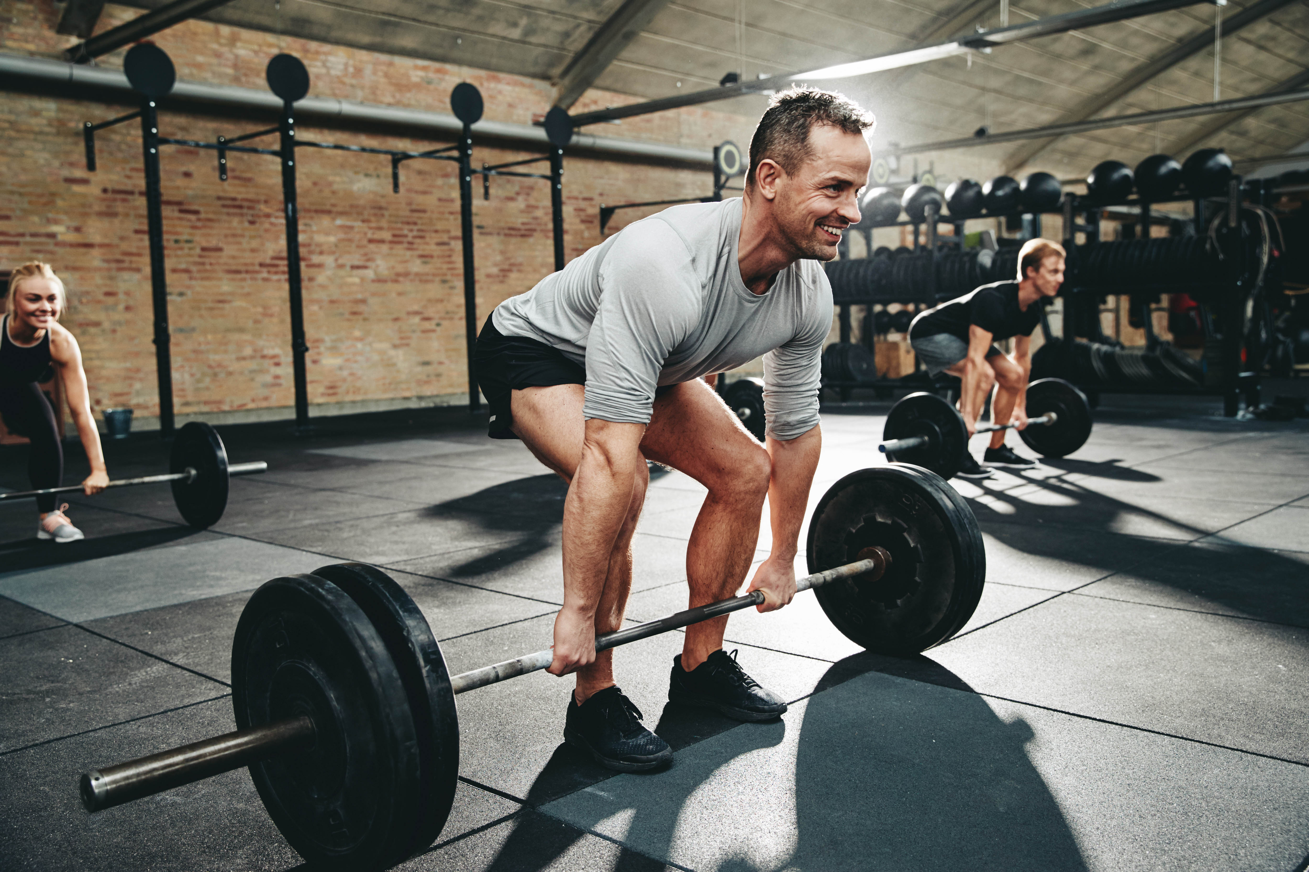 Fit man in a workout class doing a heavy deadlift at the gym